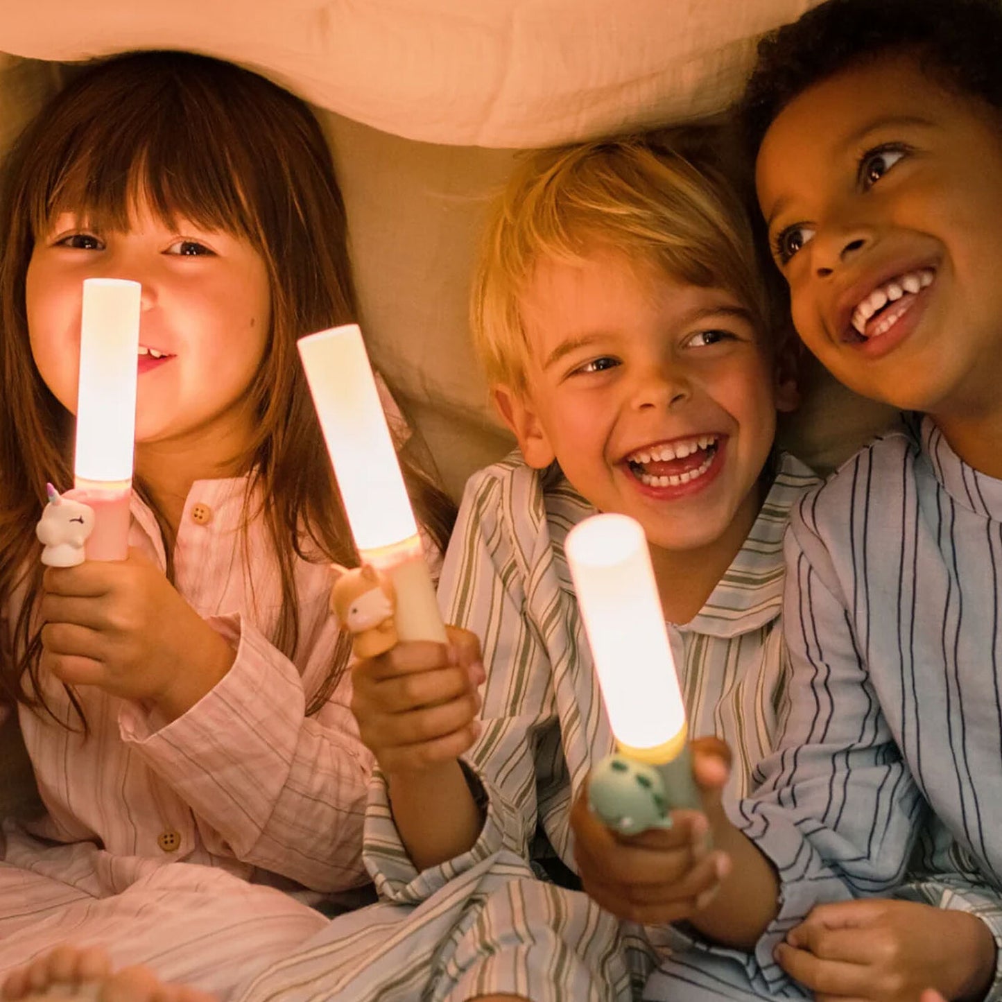 Enfants souriants jouant avec la lampe torche Dino Zoo Light dans la pénombre