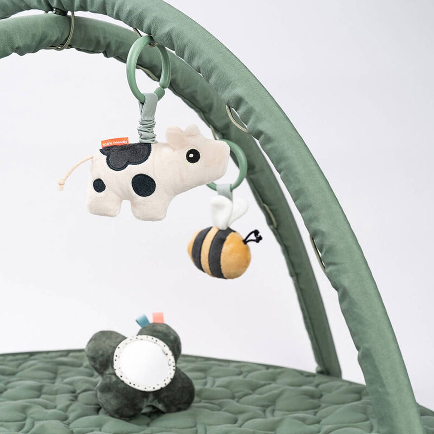 Vue de face du tapis Tiny Farm vert avec jouets suspendus