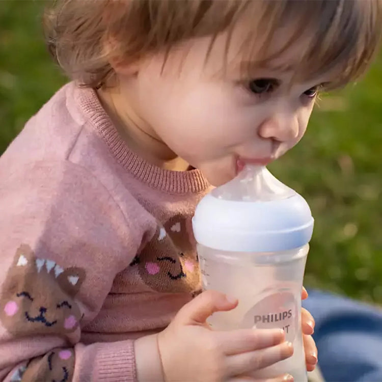 “Bébé buvant un biberon de lait dans les bras d’un parent.