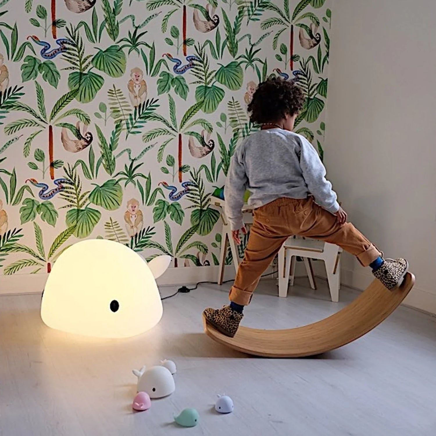 “Enfant jouant dans sa chambre à côté d’une veilleuse en forme de baleine.”