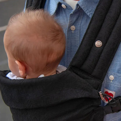 Porte-bébé ergonomique noir – papa portant son bébé confortablement contre lui, pour des balades sécurisées et pleines de tendresse.