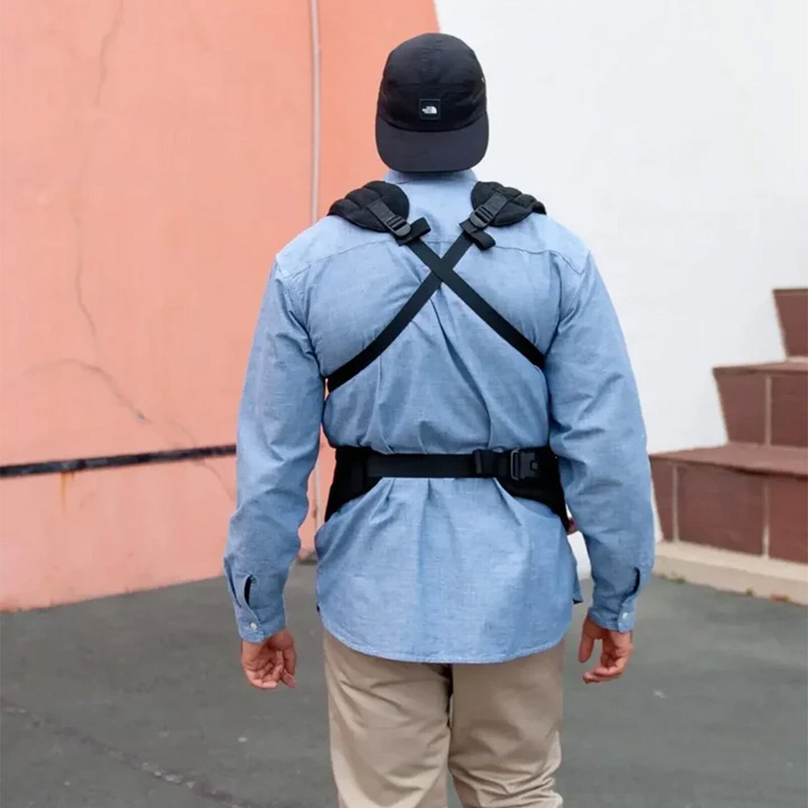 Vue arrière d’un papa portant un porte-bébé ergonomique noir – bretelles croisées pour un bon maintien et un confort optimal.