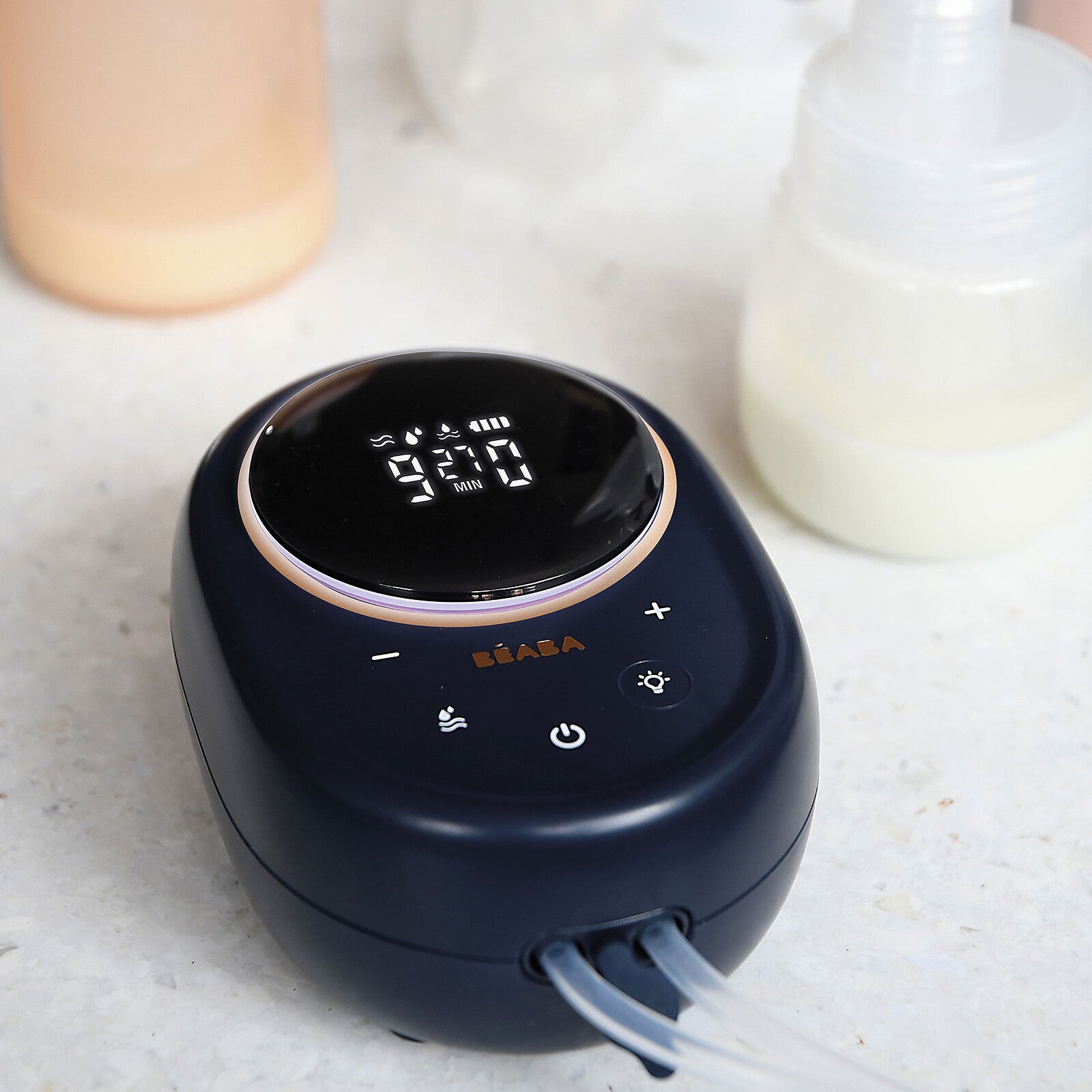 Tire-lait électrique double Béaba bleu nuit avec écran digital et biberon à côté sur une table