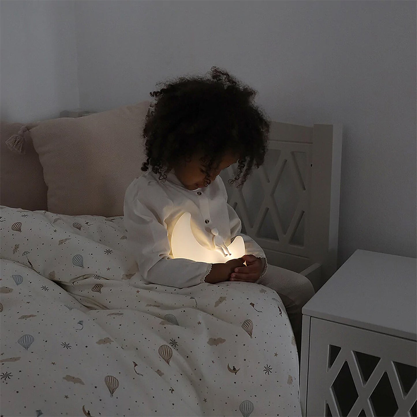 Enfant endormi dans sa chambre avec la Lampe Clair de Lune Camcam Copenhagen allumée
