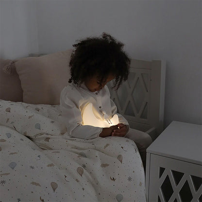 Enfant endormi dans sa chambre avec la Lampe Clair de Lune Camcam Copenhagen allumée
