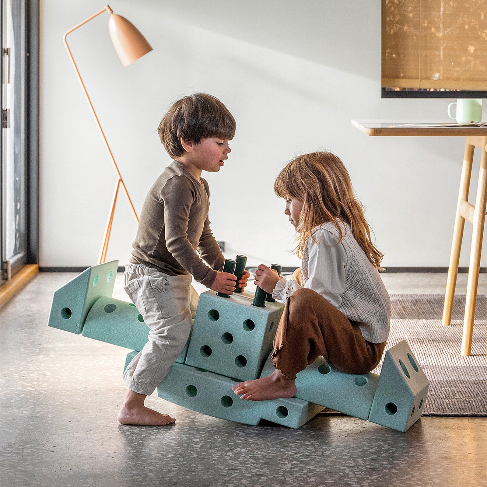 Deux enfants jouent ensemble avec le jeu de construction modulable Mobu vert, idéal pour stimuler la créativité et la motricité.