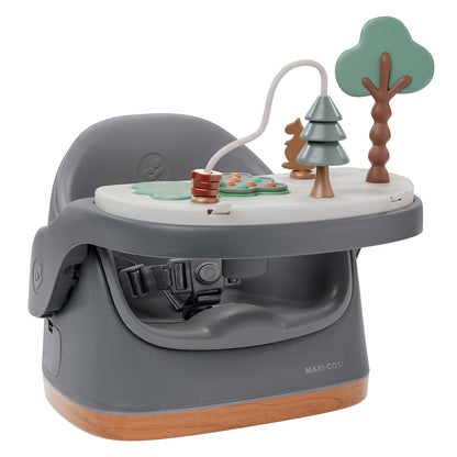 Rehausseur de chaise Maxi-Cosi Jay Plus gris posé sur une table, pratique pour les repas de bébé.