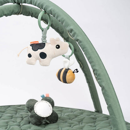 Vue de face du tapis Tiny Farm vert avec jouets suspendus